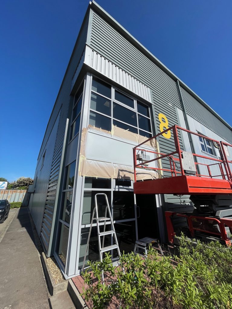 looking up at a commercial building that is having damaged panels repaired with on site paint spraying